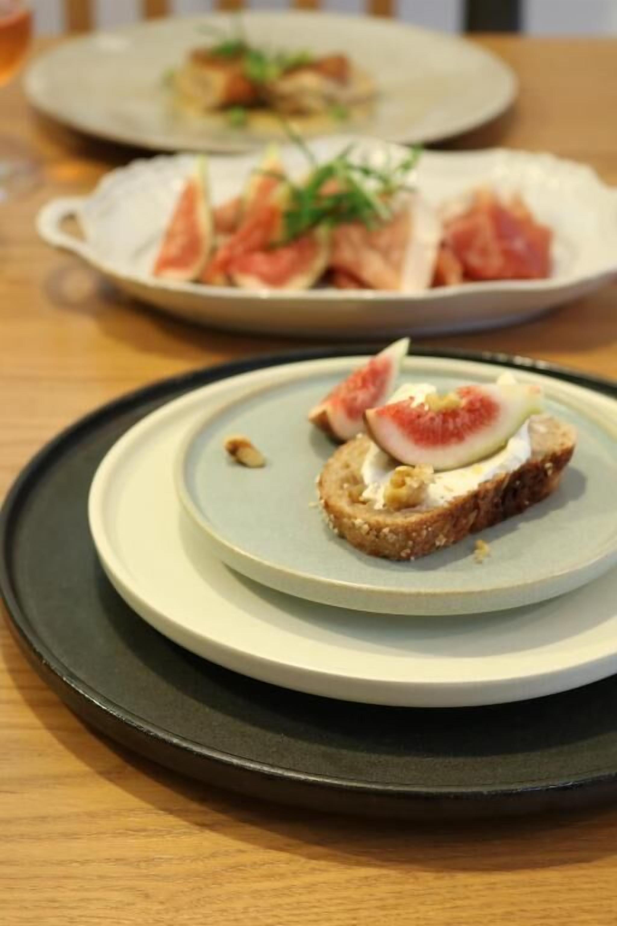A plate with a sandwich topped with a slice of tomato and a piece of cheese.