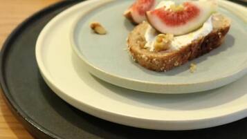 A plate with a sandwich topped with a slice of tomato and a piece of cheese.