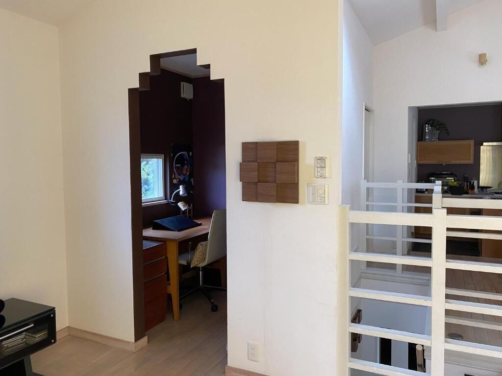 A room with a desk, chair, and a white shelving unit.