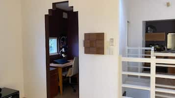 A room with a desk, chair, and a white shelving unit.