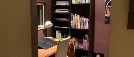 A study room with a desk, chair, bookshelf, and a small Christmas tree.