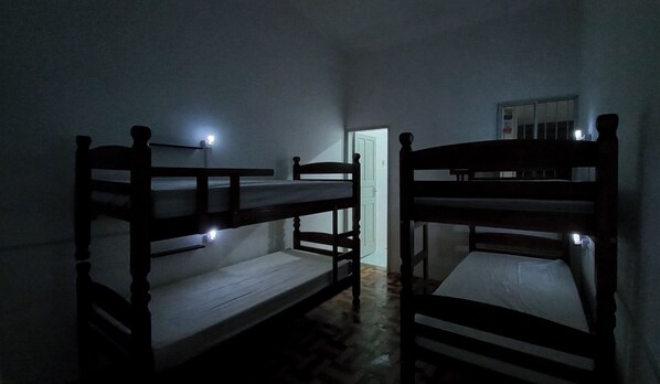 A dimly lit room with bunk beds arranged in a row. - Yolo Hostel (João Pessoa)