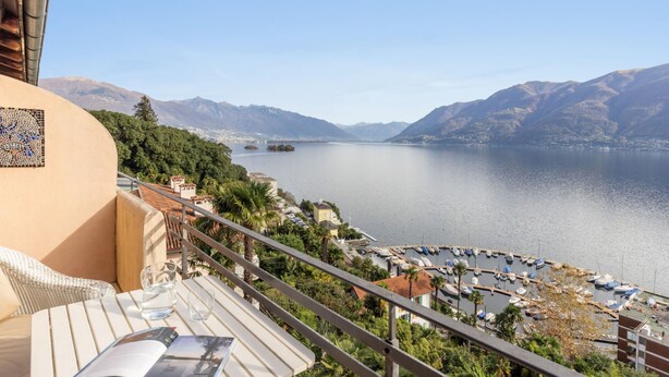 A balcony with a view of a lake, boats, and mountains.