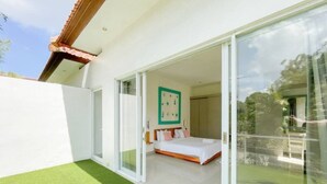 A modern bedroom with a large bed, a sliding glass door leading to a balcony, and a green wall decoration. - 3BR Del Mar Tropical Villa 4 in Seminyak Beach (Seminyak)