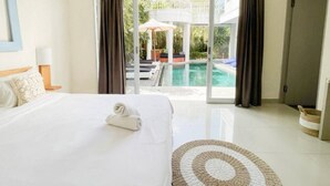 A hotel room with a bed, a view of a swimming pool, and a door leading outside. - 3BR Del Mar Tropical Villa 4 in Seminyak Beach (Seminyak)