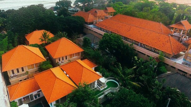 A resort with multiple buildings featuring orange tiled roofs, surrounded by lush greenery and a view of the ocean. - 3BR Del Mar Tropical Villa 4 in Seminyak Beach (Seminyak)