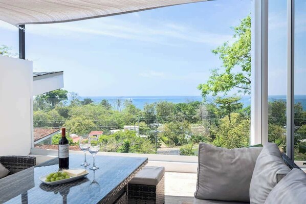 A balcony with a table, a bottle of wine, and a plate of grapes.