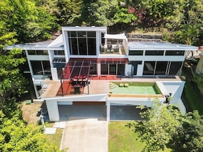A modern two-story house with large windows, a flat roof, and a swimming pool.