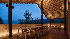 An outdoor wooden deck with a table and chairs, a pergola structure, and a view of trees and hills. - Origin Villa Hotel (Hangzhou)