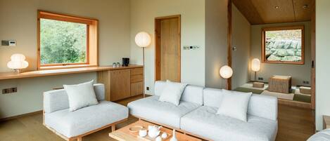 Een moderne woonkamer met een bank, een salontafel en een raam met uitzicht op groen.