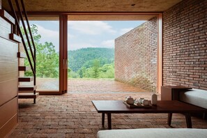Relax in a warm, rustic space with a brick floor and walls, featuring a wooden staircase and a cozy area for socializing.