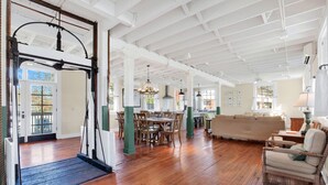 Una habitación amplia con suelo de madera, un comedor con mesa y sillas, un sofá y una silla.
