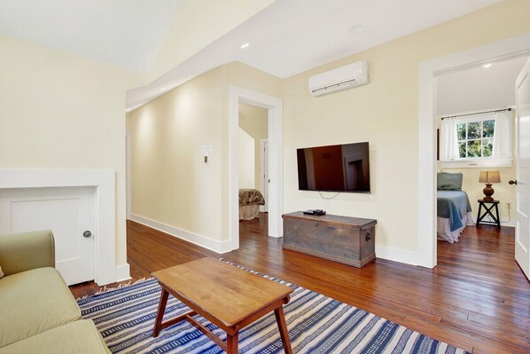 A living room with a wooden floor, a sofa, a coffee table, a TV, and a fireplace.