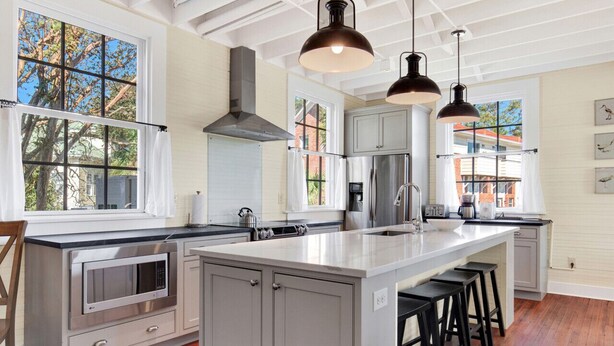 Una cocina moderna con una isla grande, electrodomésticos de acero inoxidable e iluminación colgante.