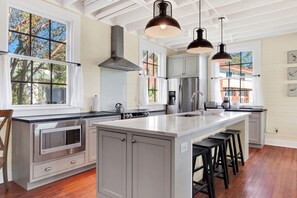 A modern kitchen with a large island, stainless steel appliances, and pendant lighting.