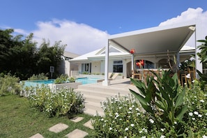 A modern house with a swimming pool, covered patio, and lush garden.