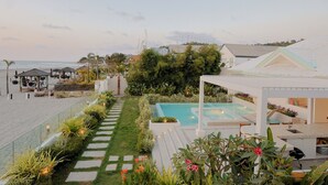 Un espace piscine agrémenté d’une balustrade en verre, d’un sentier de jardin et offrant une vue sur la plage.