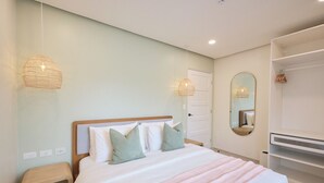 Une chambre à coucher bien aménagée, avec un lit, des tables de chevet, une armoire et des lampes suspendues.