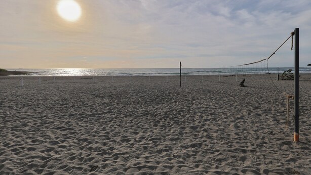 Un terrain de beach-volley avec un filet, du sable et un ciel dégagé.