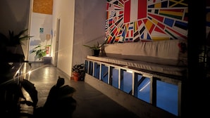 A hallway with a reception area featuring a colorful flag mural, a sofa, and potted plants. - SGH Paracas (Paracas)