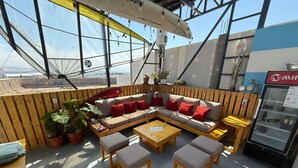 A rooftop bar with a wooden bench seating area, a refrigerator, and potted plants. - SGH Paracas (Paracas)
