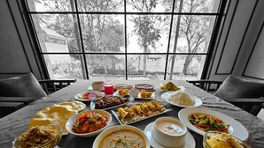 A table set with various dishes and a view of trees through large windows.