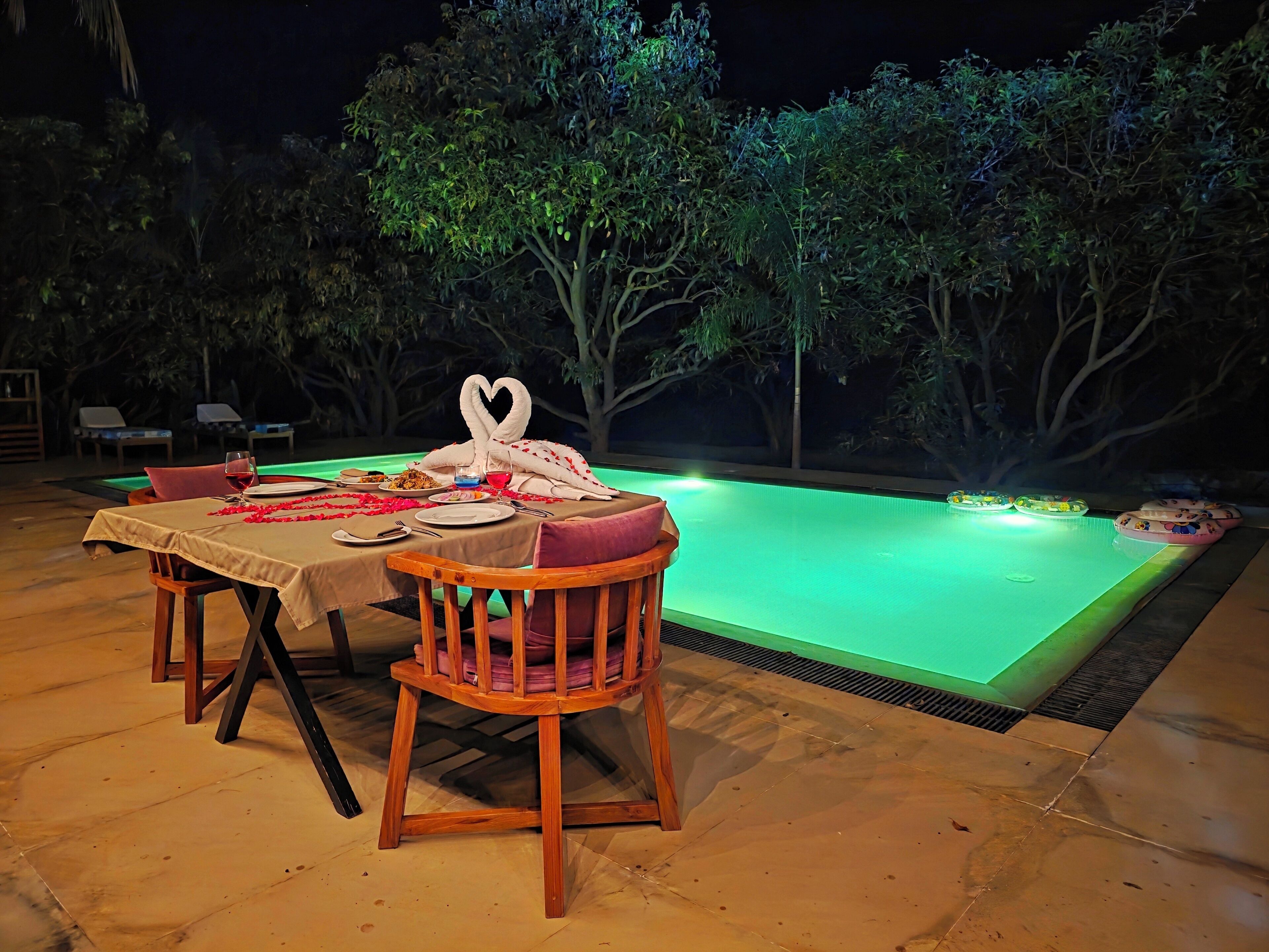 An outdoor dining area with a pool, surrounded by trees.