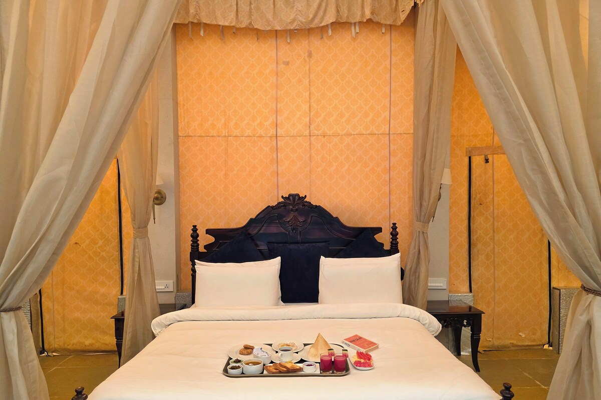 Un lit à baldaquin, un plateau de mets pour le petit-déjeuner et un mur orné de motifs.