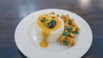 A plate of food with rice and curry, and some vegetables.
