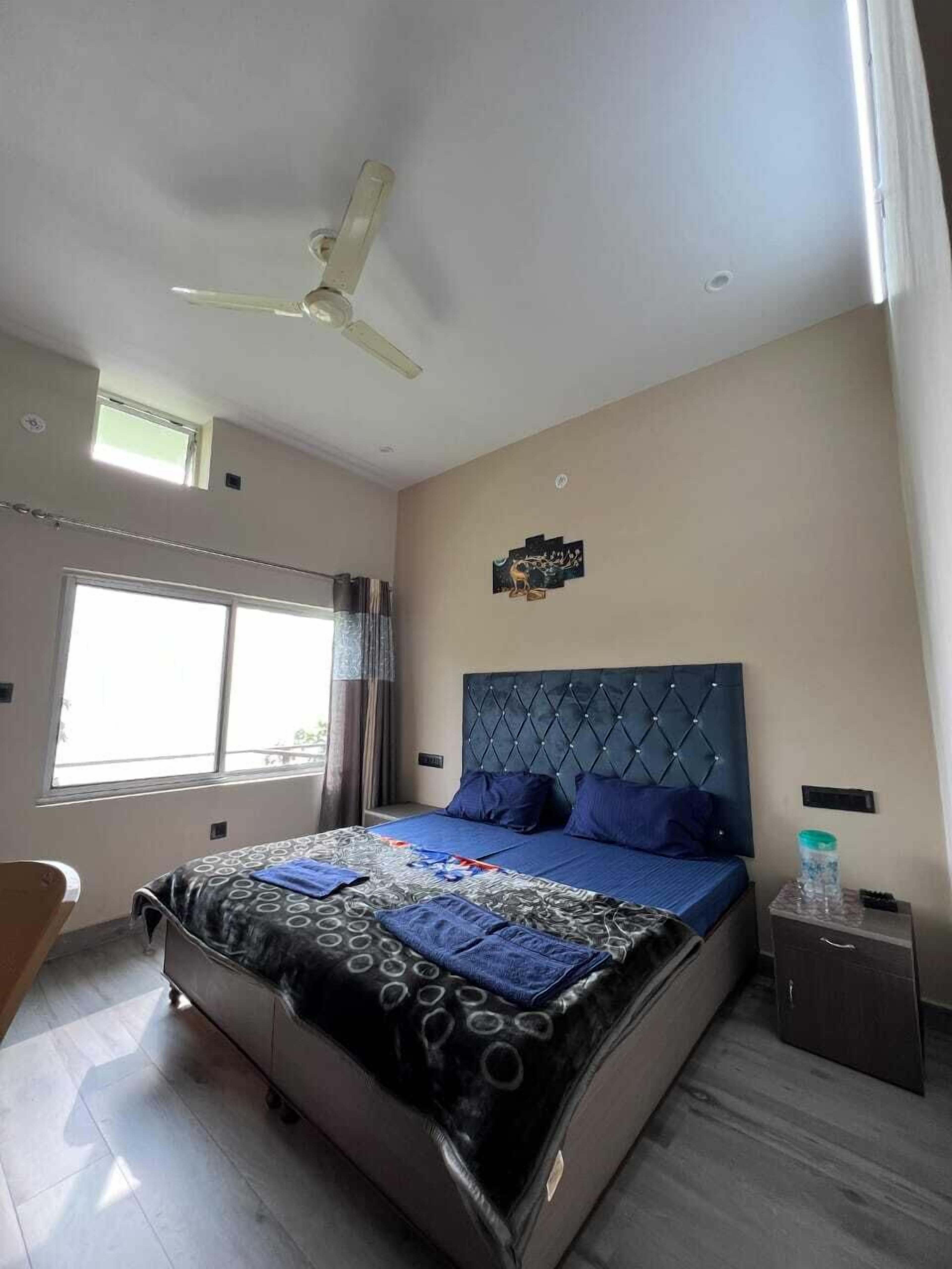 A bedroom with a bed, a ceiling fan, a window, and a nightstand.