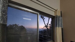 A window with a view of trees and a sunset. - Sunset View Point Homestay (Lansdowne)
