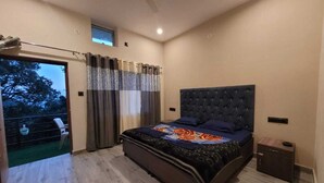 A modern bedroom with a large bed, a ceiling fan, and a view of the outdoors through a sliding door. - Sunset View Point Homestay (Lansdowne)