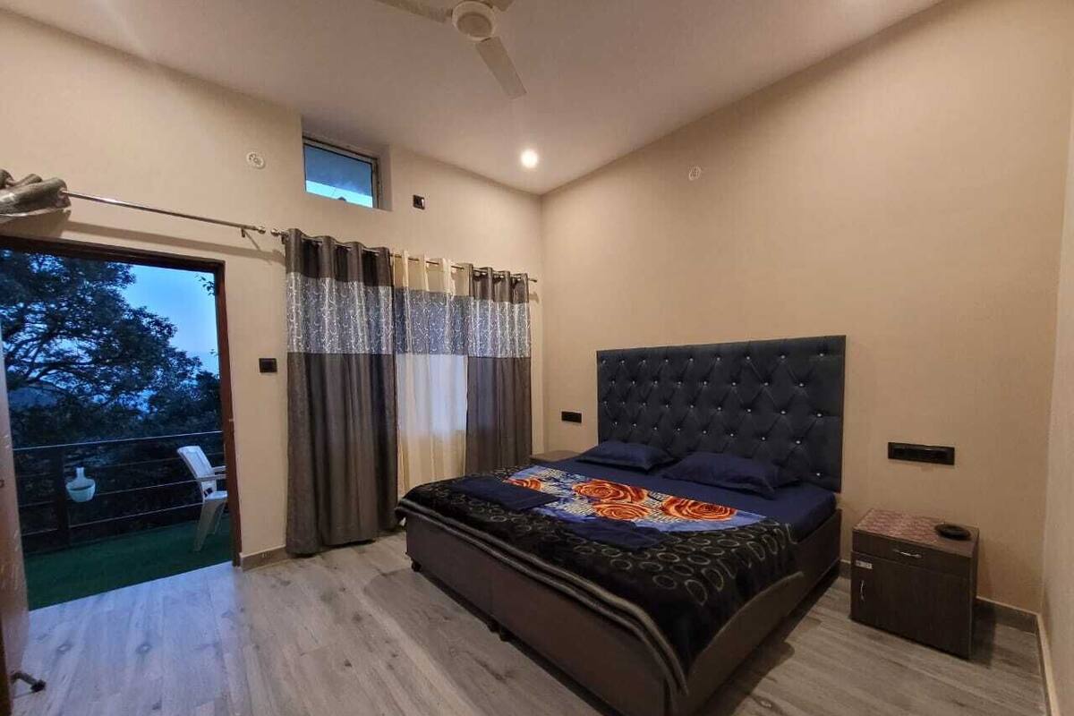 A modern bedroom with a large bed, a ceiling fan, and a view of the outdoors through a sliding door.