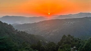 A sunset over a mountainous landscape with a valley below. - Sunset View Point Homestay (Lansdowne)