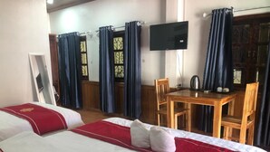 Ein Hotelzimmer mit zwei Betten, einem Fernseher, einem Holztisch und einem Stuhl.
