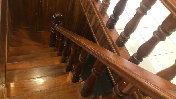 Eine Holztreppe mit Handlauf und dunklen Stufen.