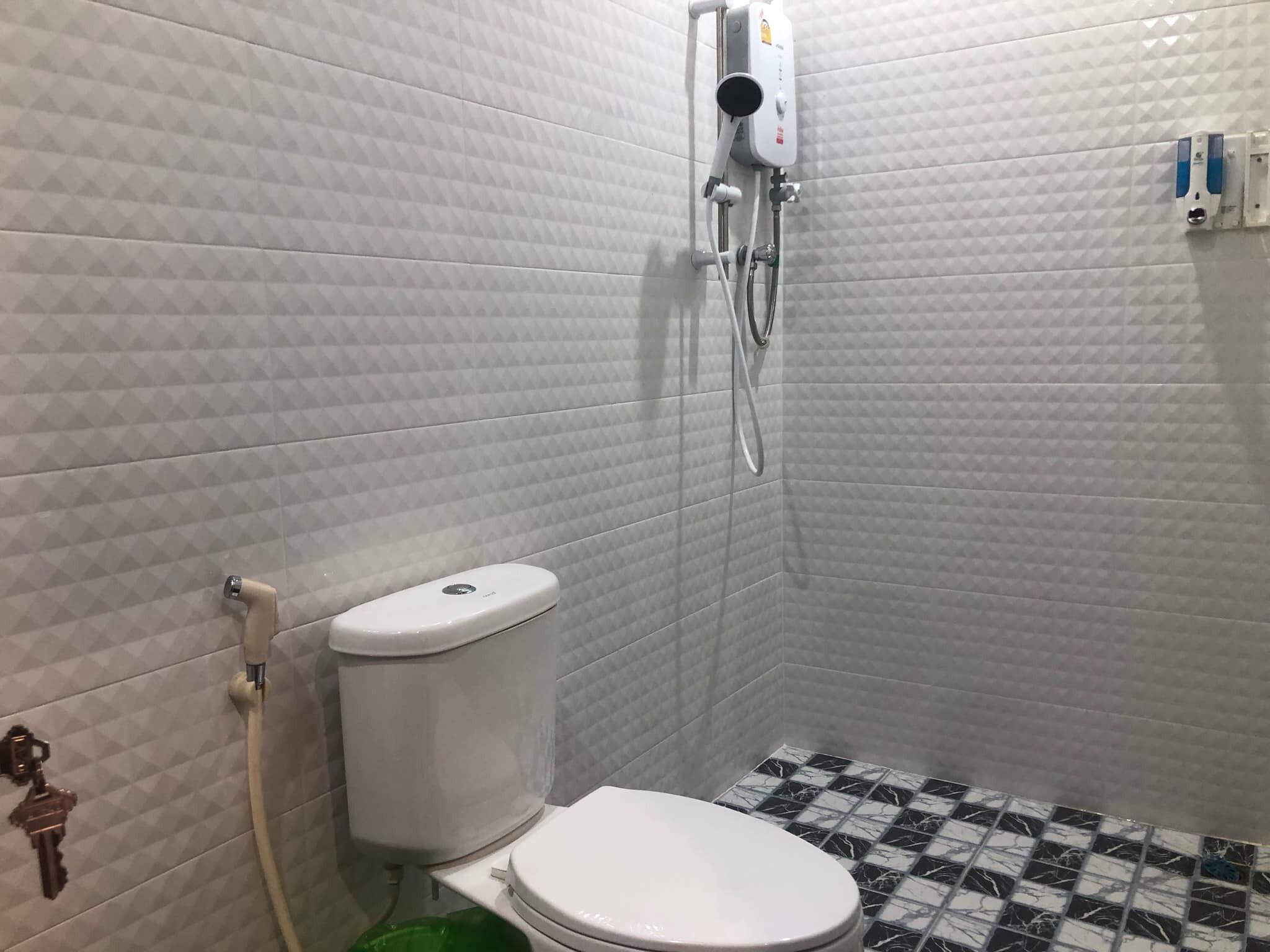 Ein kleines, kompaktes Badezimmer mit Toilette, Dusche und Fliesenboden.