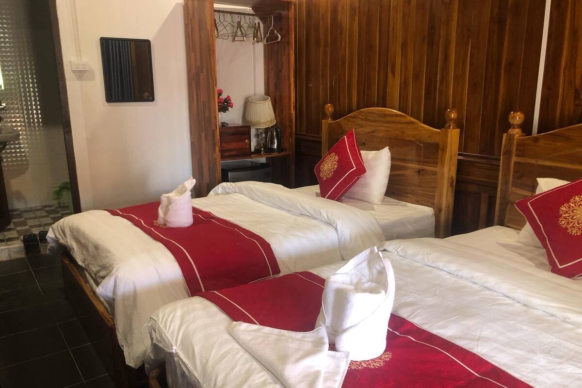A hotel room with two beds, wooden headboards, and a red and white striped bedspread.