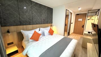 A modern hotel room with a large bed, a wooden headboard, a marble accent wall, a bedside table, and a mirror.
