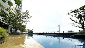 A swimming pool with a tiled edge, surrounded by greenery and modern buildings. - Howard Johnson by Wyndham Tangerang (Tangerang)