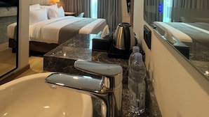 A hotel room with a large bed, a marble bathroom vanity, a sink, and a mirror. - Howard Johnson by Wyndham Tangerang (Tangerang)