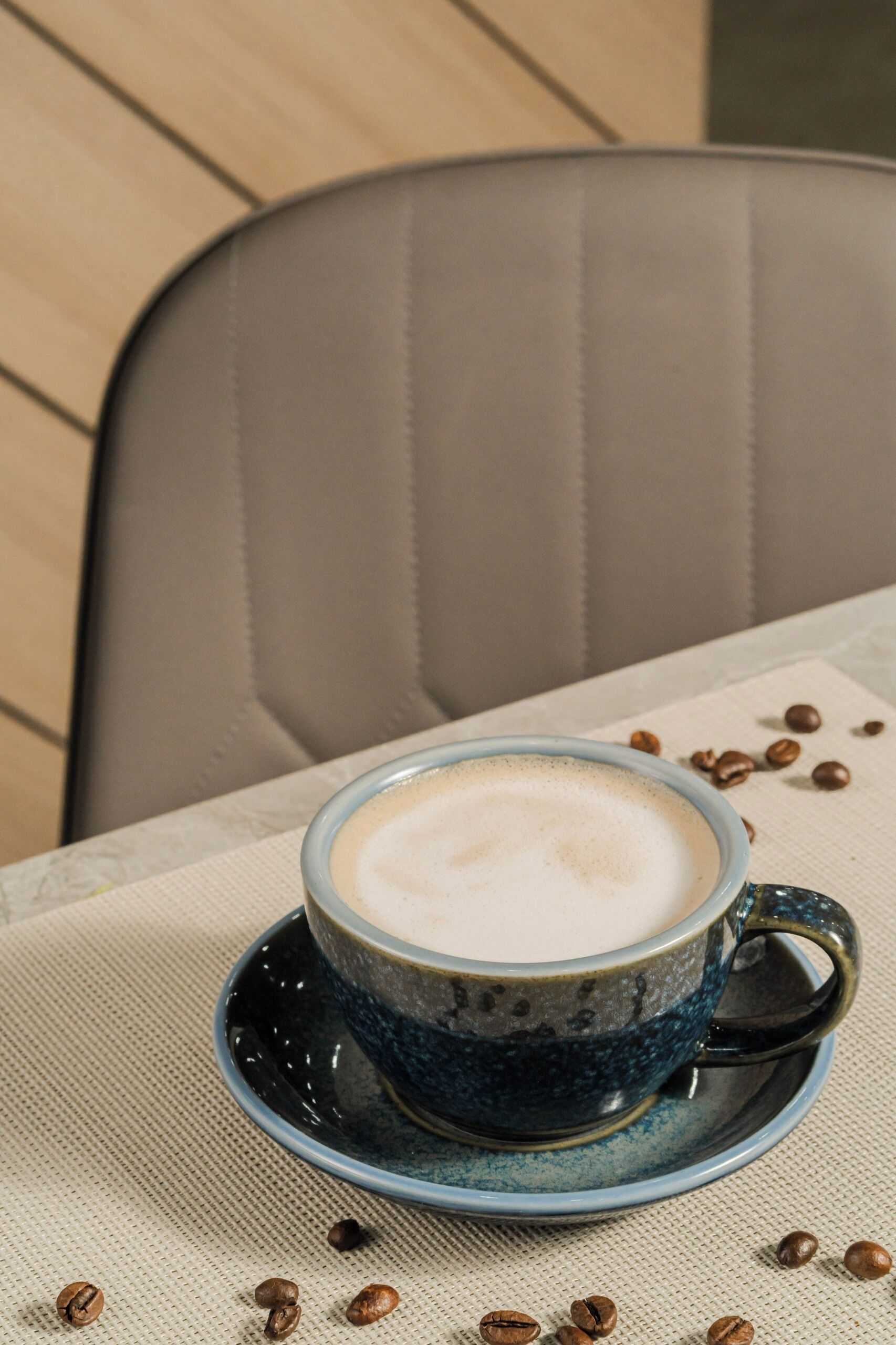 Eine Tasse Kaffee auf einem Untertasse mit verstreuten Kaffeebohnen.