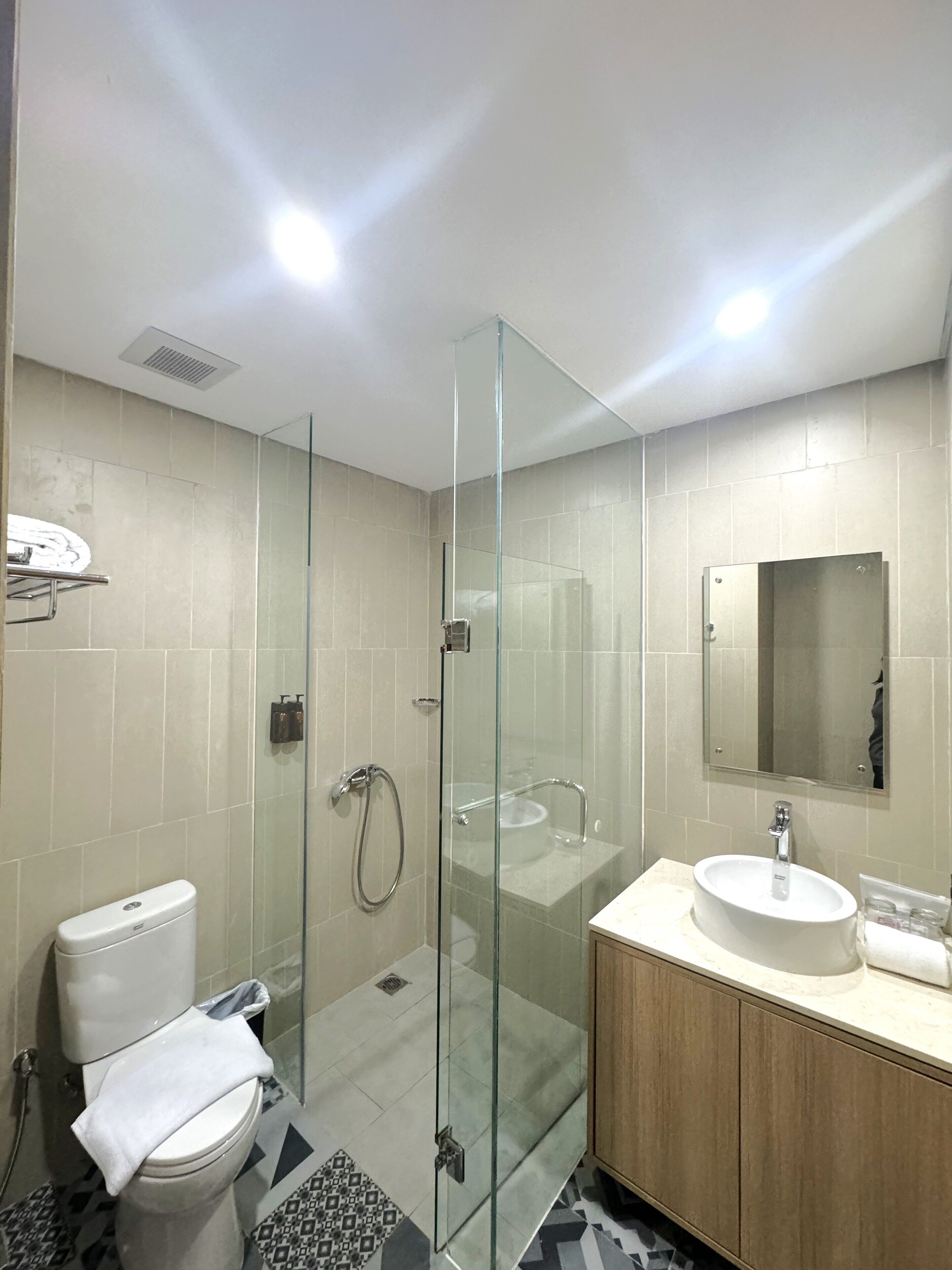Un baño moderno con ducha de vidrio, inodoro, lavamanos y espejo.
