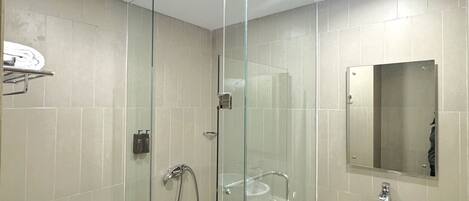 Un baño moderno con ducha de vidrio, inodoro, lavamanos y espejo.