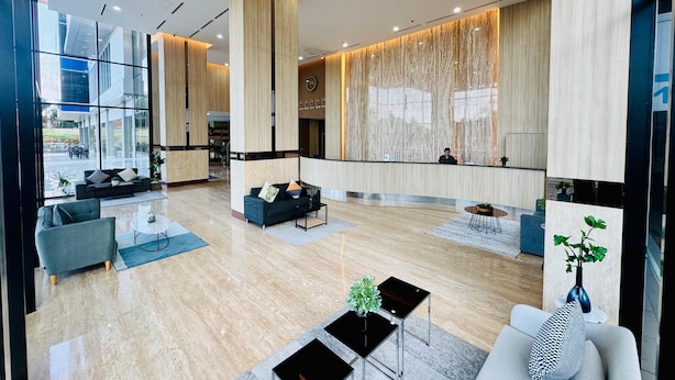 A modern hotel lobby with a reception desk, seating area, and large windows offering a view of the outdoors. - Howard Johnson by Wyndham Tangerang (Tangerang)