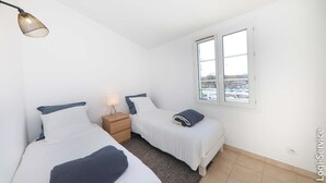 Une chambre avec deux lits, une table de chevet, une lampe et une fenêtre donnant sur un beau paysage.
