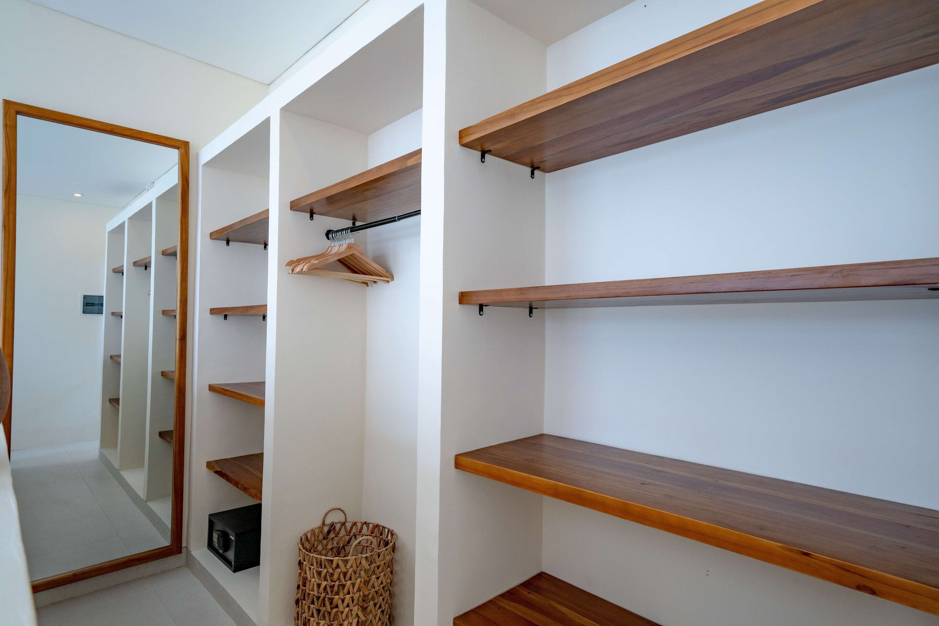 A walk-in closet with wooden shelves and a mirrored closet door.