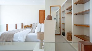 A modern bedroom with a large bed, a bedside table, a lamp, and built-in wooden shelves. - Lyma Loft (Munggu)
