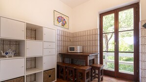 A kitchen with white cabinets, a microwave, wooden stools, and a window with a view of greenery. - Alessia, three-room apartment in Marina di Campo 250 meters from the beach, with air conditioning, p (Marina di Campo)