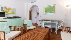 A cozy living room with a wooden table, two cushioned chairs, a teal sofa, and a television on a cabinet. - Alessia, three-room apartment in Marina di Campo 250 meters from the beach, with air conditioning, p (Marina di Campo)